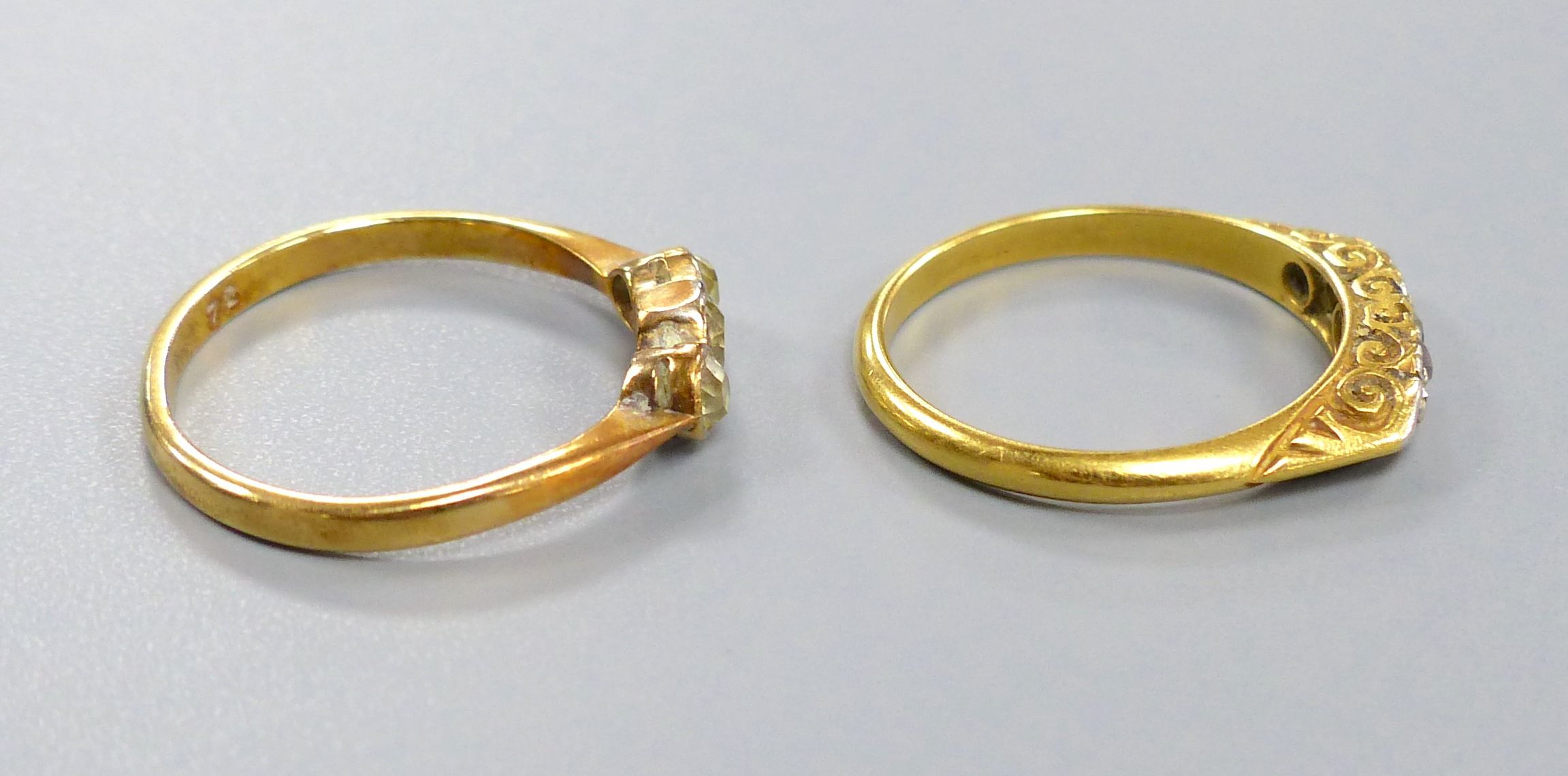 An 18ct gold three-stone diamond ring and another similar ring, gross 5.2 grams.